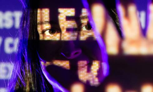 a girl on a purple background  reaches her hand out towards us with projected text overlaying the image